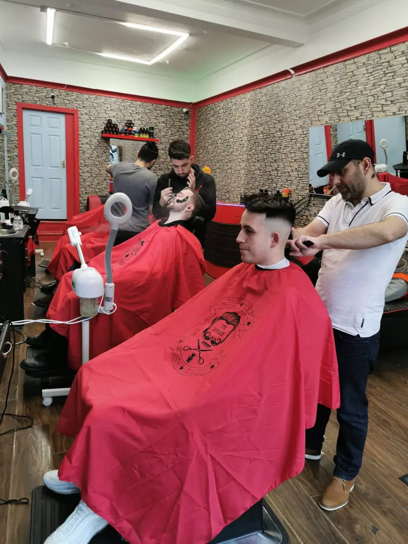Barbers working on clients in red capes
